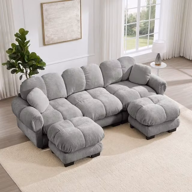 Divano modulare a U OKWISH in velluto grigio con pouf e cuscini decorativi L: 260 cm, P: 149 cm, H: 90 cm