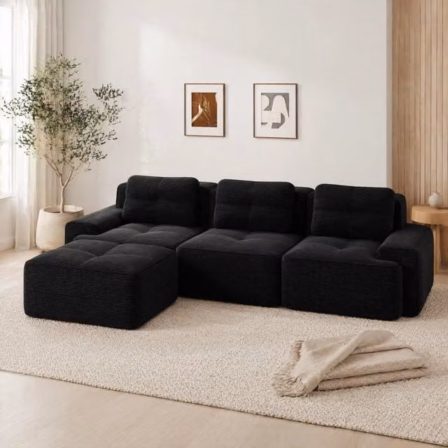 Divano modulare a L Mivray in velluto a coste nero con seduta profonda 74 cm e braccioli larghi