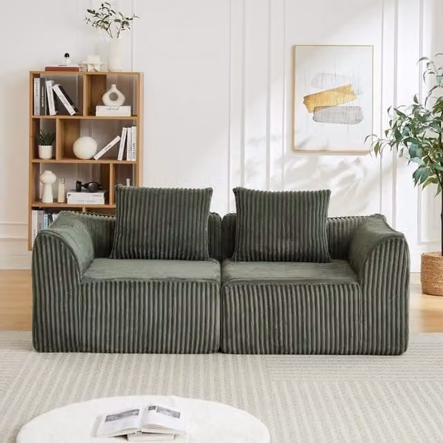 Divano minimalista in velluto a coste con linee curve e schienale dolcemente inclinato, completo di due cuscini