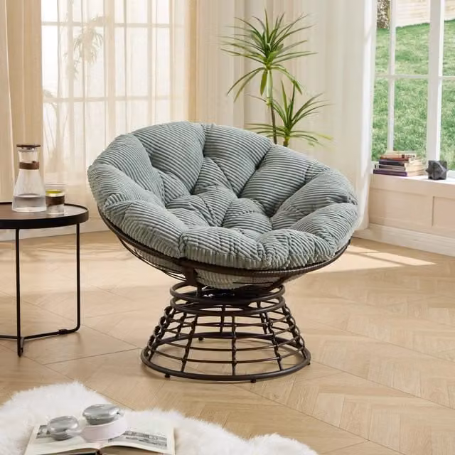 Poltrona Papasan in rattan ergonomica, girevole 360°, per interni/esterni. Telaio marrone, cuscino spesso verde chiaro in velluto a coste, delicato sulla pelle