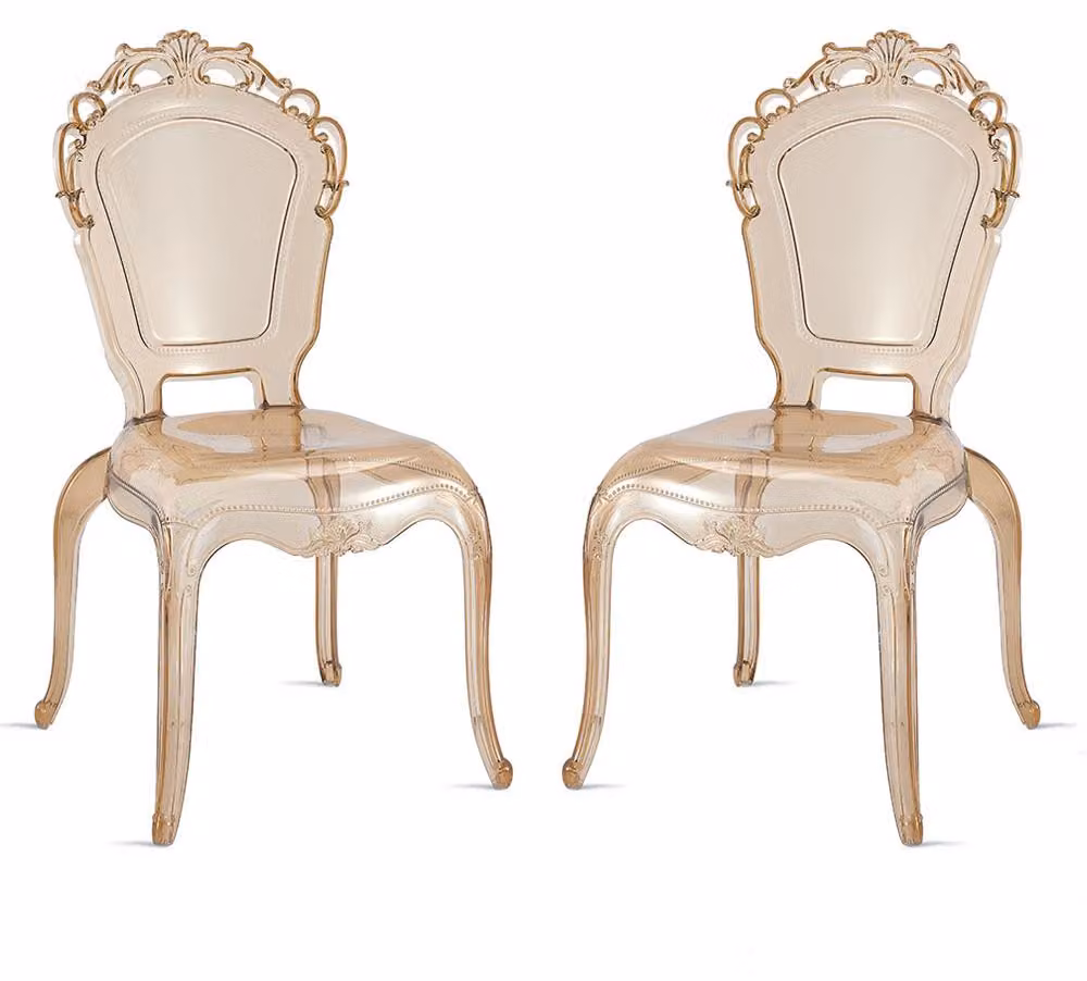 Set di 2 sedie impilabili in policarbonato trasparente, in stile barocco moderno, con piedini antiscivolo, adatte per interni, aree esterne coperte,da pranzo e ristoranti. Modello Maya/Champagne