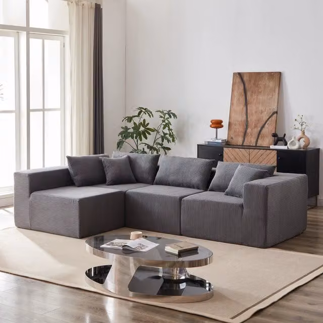 Divano angolare modulare a L Mivray in velluto a coste grigio con seduta ampia e cuscini coordinati per soggiorno e camera da letto
