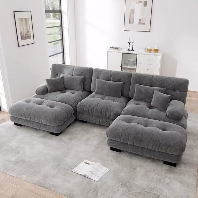 Divano angolare modulare OKWISH in velluto grigio con pouf e cuscini coordinati, design moderno a forma di L con seduta sinistra