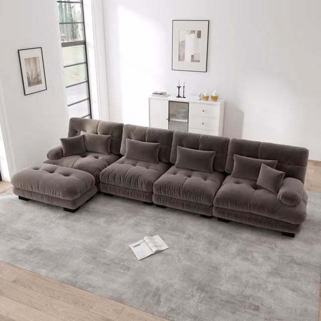 Divano angolare modulare OKWISH in tessuto moderno con ottomana coordinata e cuscini, disponibile nei colori marrone o grigio