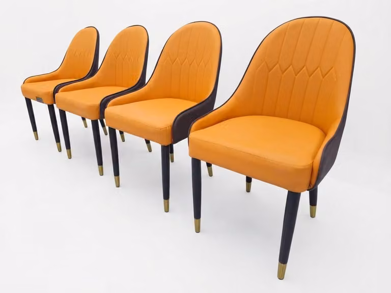 Quattro eleganti sedie, rivestite in pelle arancione, con schienale scuro